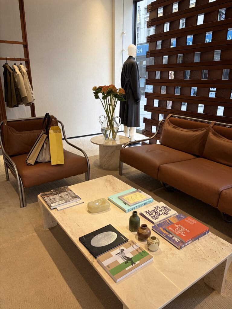 Interior des neuen Max Mara Flagship-Stores in München mit braunen Ledermöbeln, Naturstein-Tisch und reduzierter Warenpräsentation.