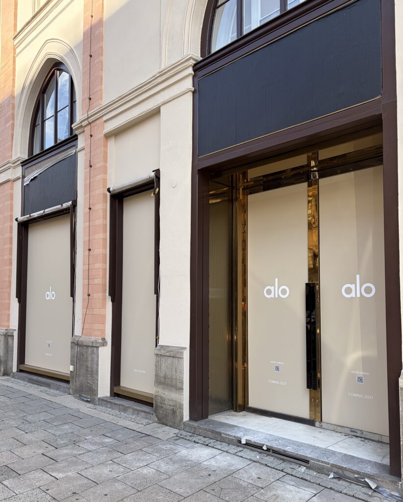 Fassade des angekündigten Alo Stores in München mit verklebten Schaufenstern und Hinweis „Coming 2027“