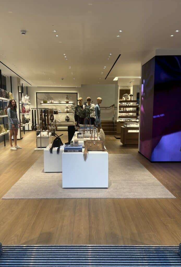 Innenansicht des Michael Kors Stores mit Taschen, Accessoires und modernem Store-Design.