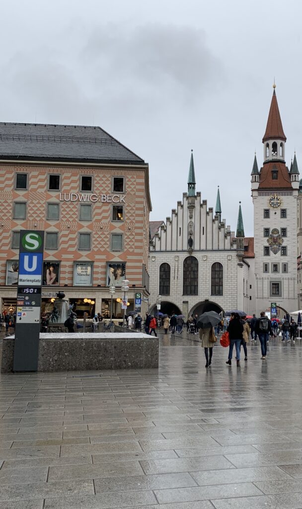 Blick auf den Marienplatz in München mit dem Modehaus Ludwig Beck, dem Neuen Rathaus und dem Alten Peter im Hintergrund. Das traditionsreiche Kaufhaus zählt zu den bekanntesten Shopping-Adressen der Münchner Innenstadt.