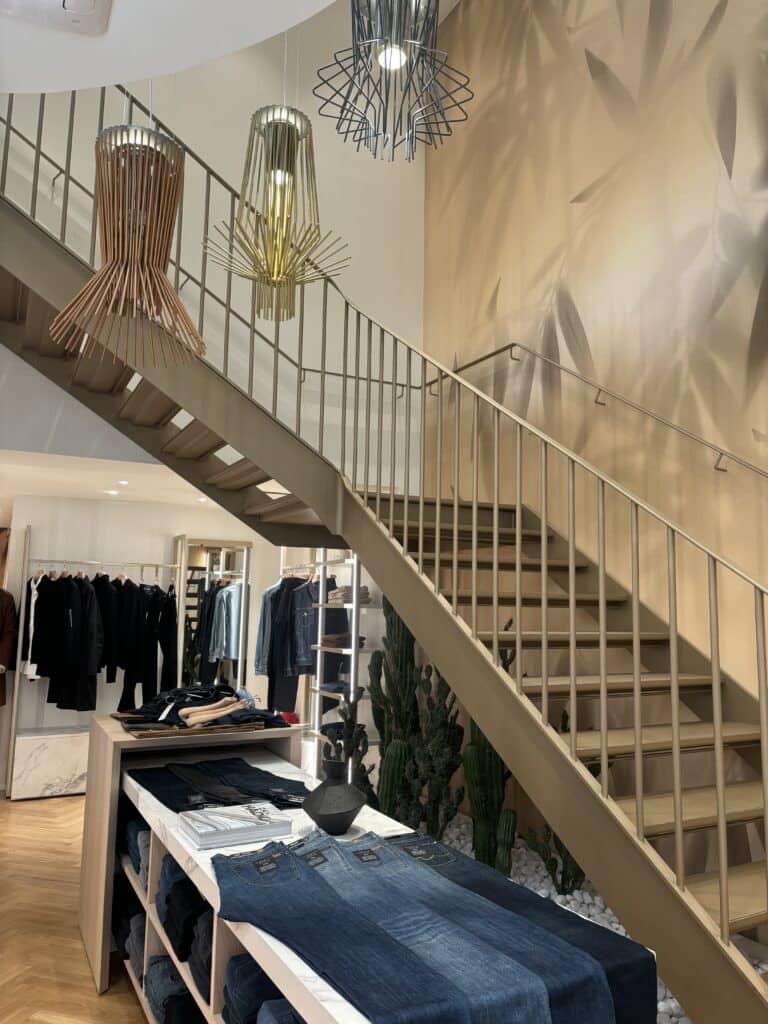 Stylischer Innenbereich des 7 For All Mankind Stores mit Treppenaufgang, Lampen und modernem Design.