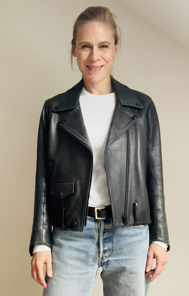 Personal Stylistin Heide von STYLEFINDS trägt eine schwarze Lederjacke zu weißem T-Shirt und heller Straight Leg Jeans und zeigt, wie eine Jacke die Wirkung eines Outfits verändert.